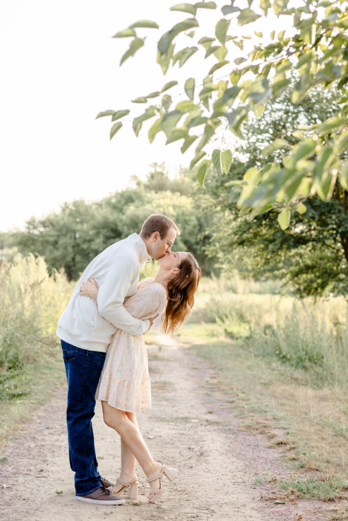 bride and groom kissing in green scenery for engagement photo